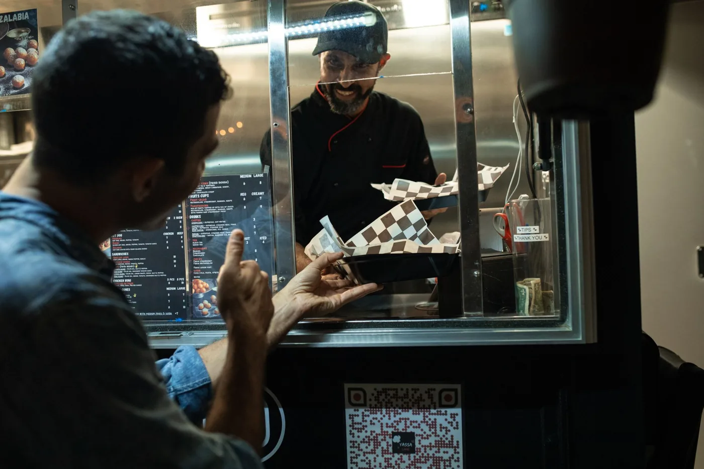 A smartphone being held over a QR code printed on a restaurant table card, with a digital menu visible on screen